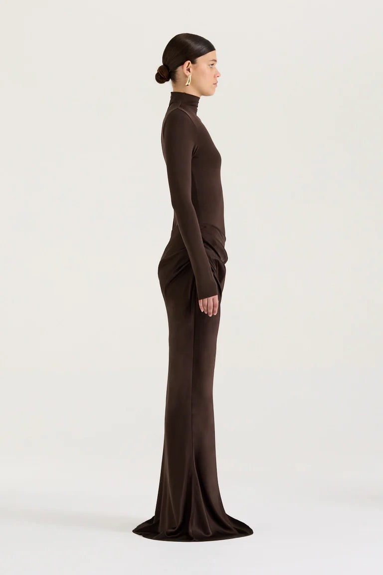 Woman wearing a brown long-sleeve top and long skirt set on a white background